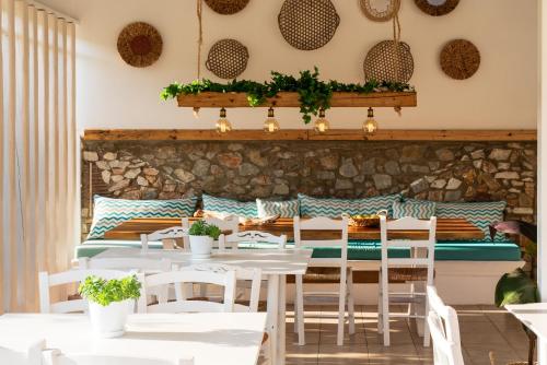 a restaurant with white tables and chairs and a stone wall at Almira Hotel in Troulos