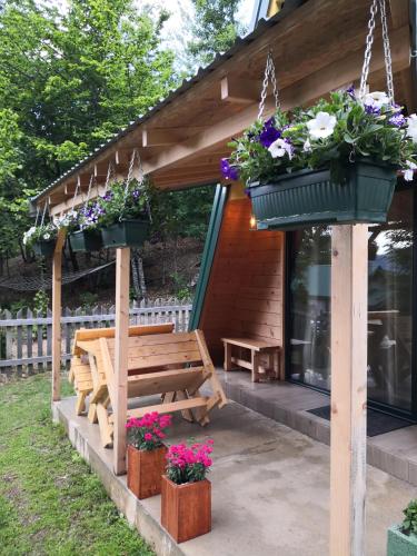 a wooden bench under a gazebo with flower pots at Koliba Pčelica 2 in Bijelo Polje