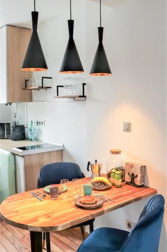 une cuisine avec une table en bois et des chaises bleues dans l'établissement La suite d'Etretat, à Étretat