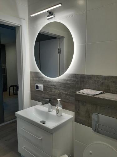 een badkamer met een witte wastafel en een spiegel bij Apartament Miętowa Perła in Kołobrzeg