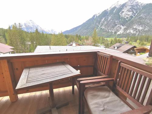a balcony with a bench and a table and a mountain at Schickster Sky Lodge in Leutasch