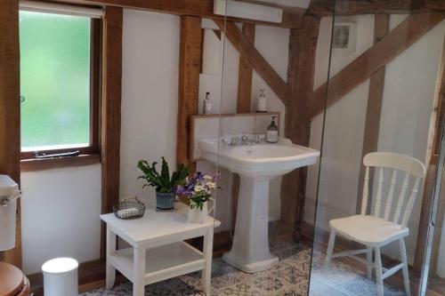 a bathroom with a white sink and two chairs at Cosy listed barn in peaceful country village in Grandborough