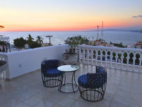 a balcony with chairs and a table with a view of the ocean at Villa Guitarron gran terraza vista espectacular 6 huespedes piscina gigante in Acapulco