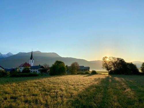 a church in the middle of a field with the sun setting at Avio rooms in Cerklje na Gorenjskem