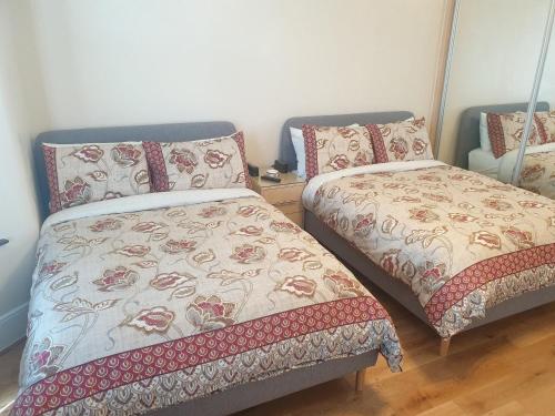 a bedroom with two beds and a bedspread with flowers at London Luxury Apartments 5 min walk from Ilford Station, with FREE PARKING FREE WIFI in Ilford
