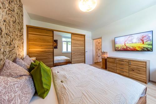 a bedroom with a large bed and a flat screen tv at Murtal Suiten in Zeltweg