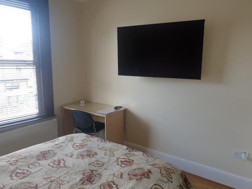 a bedroom with a bed and a desk and a television at London Luxury Apartments 5 min walk from Ilford Station, with FREE PARKING FREE WIFI in Ilford