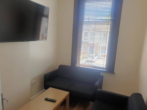 a small living room with a couch and a tv at London Luxury Apartments 5 min walk from Ilford Station, with FREE PARKING FREE WIFI in Ilford