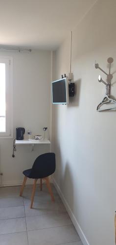 a room with a chair and a tv on a wall at Hôtel restaurant du Commerce in Poulainville