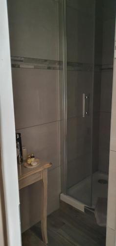 a shower with a glass door next to a table at Hôtel restaurant du Commerce in Poulainville