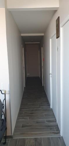 a hallway with a long corridor with white walls and tile floors at Hôtel restaurant du Commerce in Poulainville