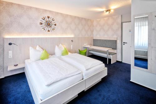 a bedroom with a large white bed and a desk at Hotel Restaurant Kerzenstüble in Gärtringen
