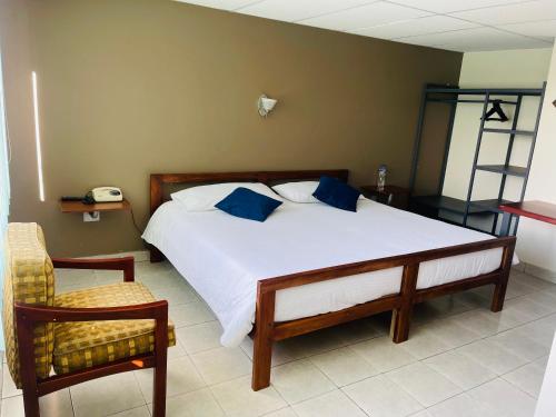 a bedroom with a bed with blue pillows and a chair at El Balcon de los Reyes in Ibarra
