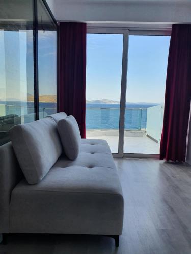 a living room with a couch and large windows at Hotel Aloha in Sarandë