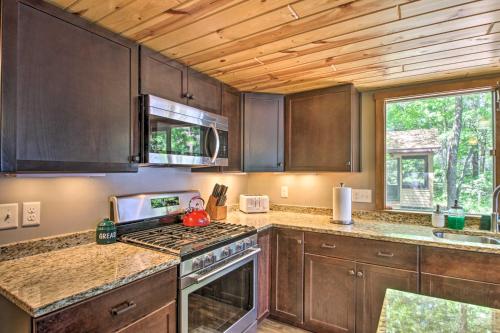 a kitchen with wooden cabinets and a stove top oven at Loon Lake Lodge with Dock, Sauna and Hot Tub! in Pequot Lakes