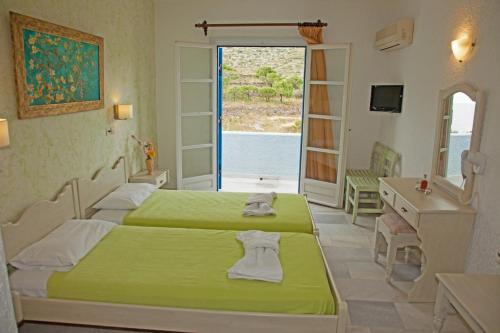 een slaapkamer met 2 bedden, een wastafel en een spiegel bij St.George Valsamitis in Katápola