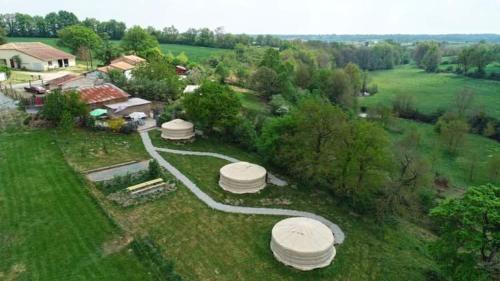 une vue sur une ferme avec des dômes dans un champ dans l'établissement Aux Yourtes de La Fabrique, à Saint-Florent-des-Bois