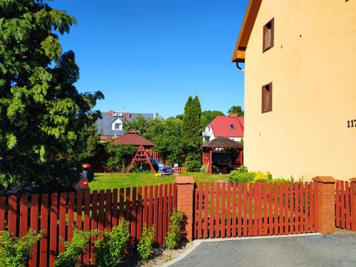 una valla roja frente a una casa con parque infantil en 117 en Łeba