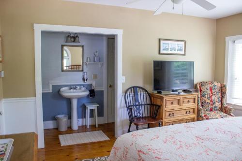 a bedroom with a bed and a sink and a television at Bourne Bed and Breakfast in Ogunquit