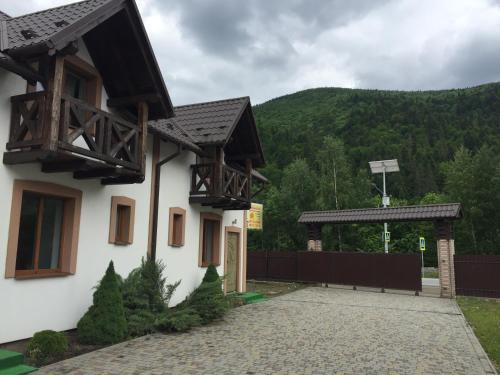 a white building with a gate and a mountain at Карпатський Готель Олександрія in Mykulychyn
