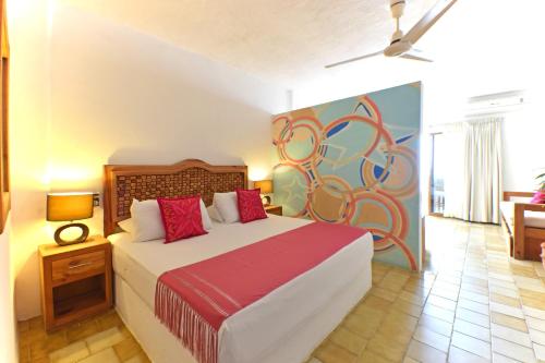 a bedroom with a bed with a painting on the wall at Emperador Vallarta Beachfront Hotel and Suites in Puerto Vallarta