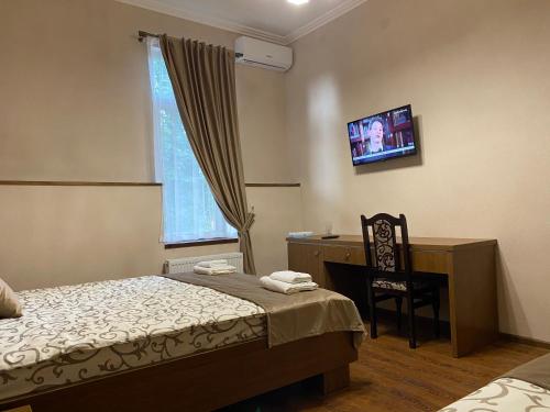 a bedroom with a bed and a desk and a television at Grand Hotel in Mohyliv-Podilʼsʼkyy