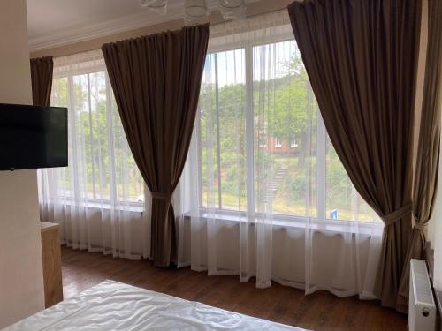 a bedroom with a large window with curtains at Grand Hotel in Mohyliv-Podilʼsʼkyy