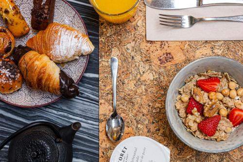 a table with a bowl of cereal and a plate of croissants and strawberries at Hotel Margot House Barcelona in Barcelona