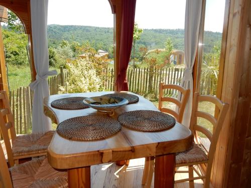 Fount de Cousteno في Limbrassac: طاولة خشبية عليها اربعة اطباق امام النافذة