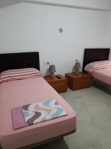een slaapkamer met 2 bedden en 2 nachtkastjes bij pension mexico in Alicante