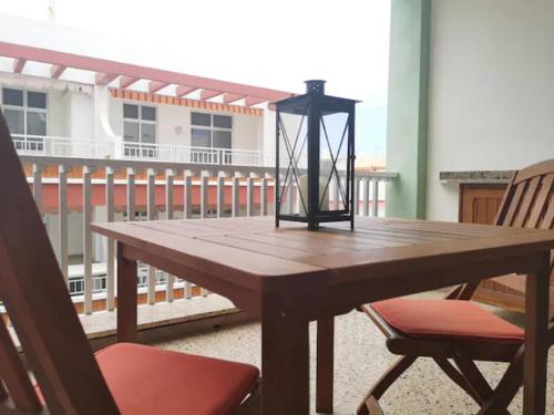 a wooden table with two chairs and a lantern on a balcony at Casa Naos in Puerto Naos