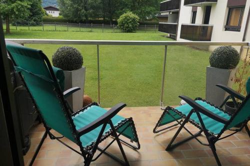 two green chairs on a patio with a view of a yard at Appartement meublé tout confort in Scionzier
