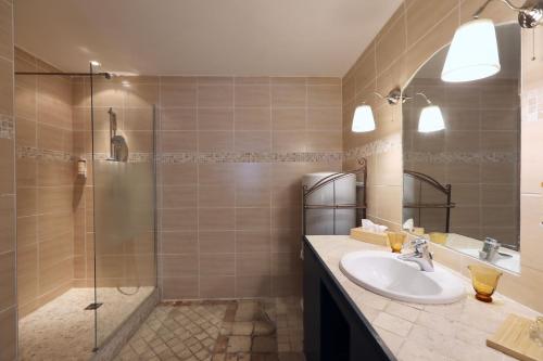 La salle de bains est pourvue d'un lavabo et d'une douche. dans l'établissement Les Canoubiers Luxe et sérénité au cœur de Saint-Tropez Suites spacieuses avec jardin enchanteur, à Saint-Tropez