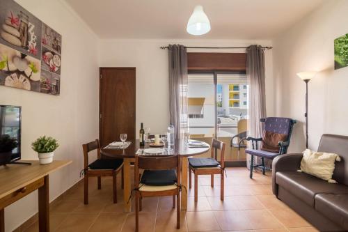 a living room with a table and chairs and a couch at Armação Beach Residences in Armação de Pêra