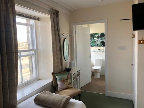 1 dormitorio con ventana, silla y aseo en The Aberdeen Arms Hotel en Tarves