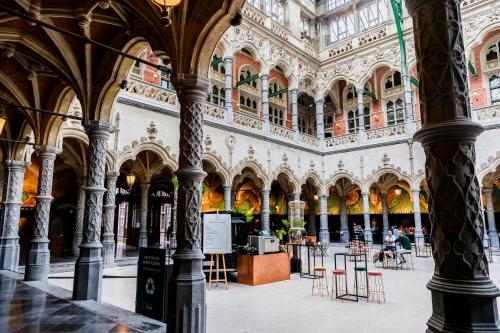 a large building with columns and tables in it at Hotel Indigo Antwerp City Centre by IHG in Antwerp