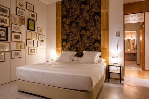 a bedroom with a large white bed and a wall with pictures at Hotel Margot House Barcelona in Barcelona