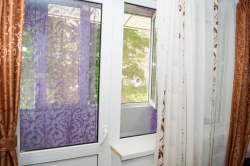 a window with a purple curtain next to a door at Apartament 2 camere in Haţeg