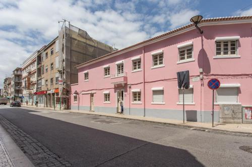 a pink building on the side of a street at Family Home- Lisboa in Vila Franca de Xira