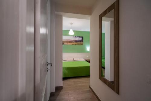 a bedroom with a green bed and a mirror at La Duchessa e Il Contadino in Vieste
