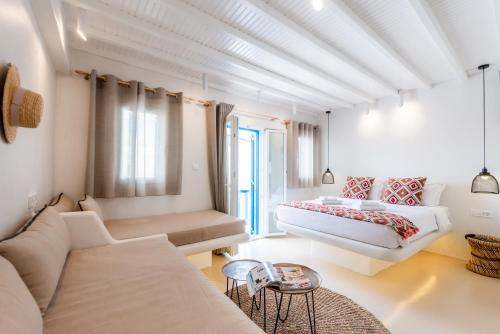 a white bedroom with a bed and a couch at Anastasia's Visage Stylish Accommodation Rooms City Centre Mykonos in M&yacute;konos City