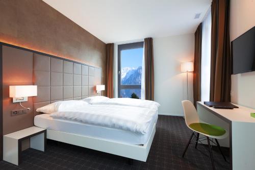 ein Hotelzimmer mit einem Bett, einem Schreibtisch und einem Fenster in der Unterkunft b-smart motel Sevelen in Sevelen