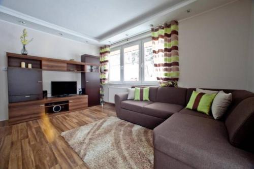 a living room with a couch and a flat screen tv at Apartament Oliwkowy in Szklarska Poręba