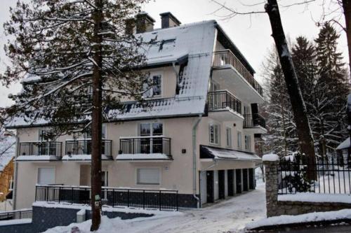 a large white building with snow on it at Apartament Oliwkowy in Szklarska Poręba