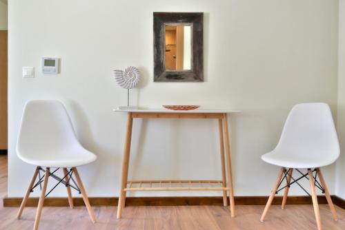 two white chairs sitting next to a table with a mirror at Onar Hydra in Hydra