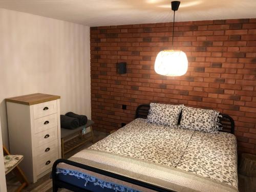 a bedroom with a bed and a brick wall at Apartamenty Chris in Augustów