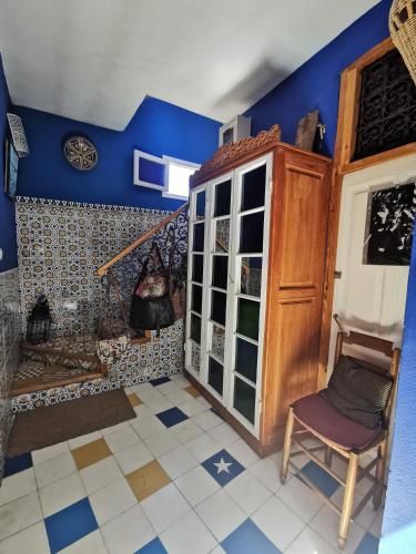 a room with a staircase and blue walls and a chair at Bayt Alice Hostel in Tangier