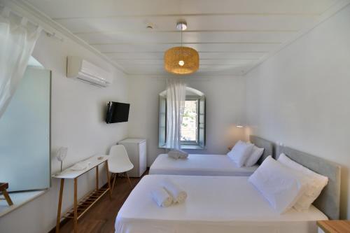 a bedroom with two beds and a window at Onar Hydra in Hydra