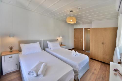 two beds in a room with white sheets at Onar Hydra in Hydra