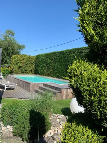a swimming pool in a garden with bushes at Pont du Chalon Hôtel and Restaurant in Margès
